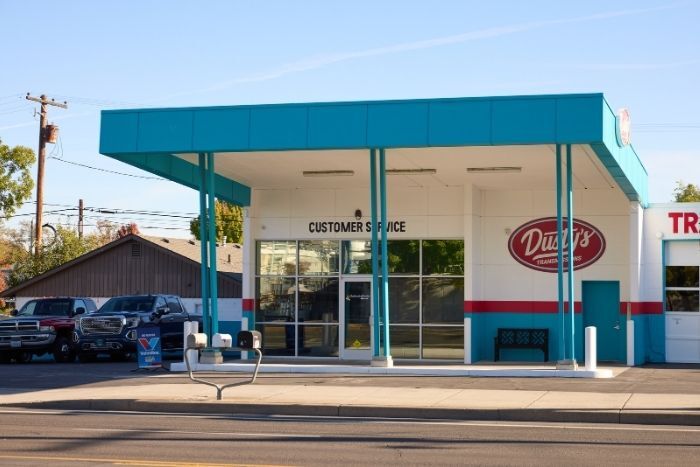 Exterior of an auto service building with large windows, labeled "Customer Service" and a red Dusty's sign.
