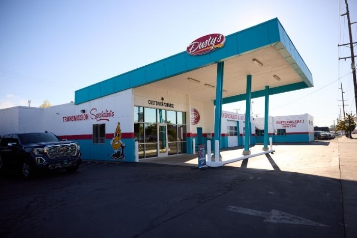 Dusty’s Transmission and Service building with teal roof, glass doors, and sunny blue sky background.